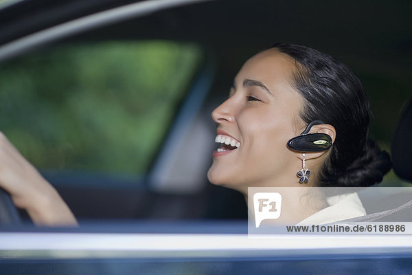 Hispanic woman driving with hands-free cell phone device
