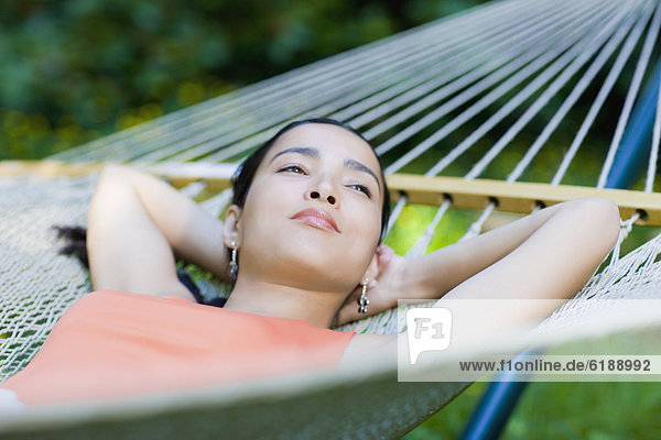Hispanic woman laying in hammock