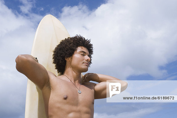 African man at beach with surfboard
