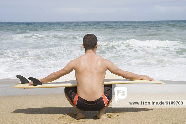 Hispanic man with surfboard at beach