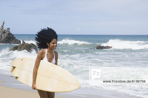 African woman with surfboard at beach