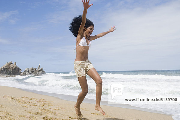 African woman jumping at beach