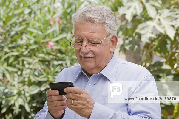 Senior Chilean man text messaging on cell phone