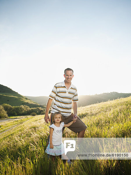 Father and daughter standing together in field
