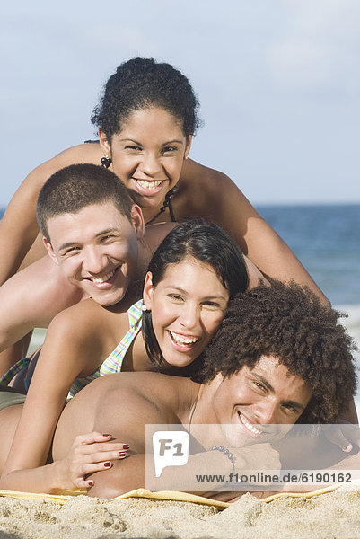 Multi-ethnic friends laying in pile on beach