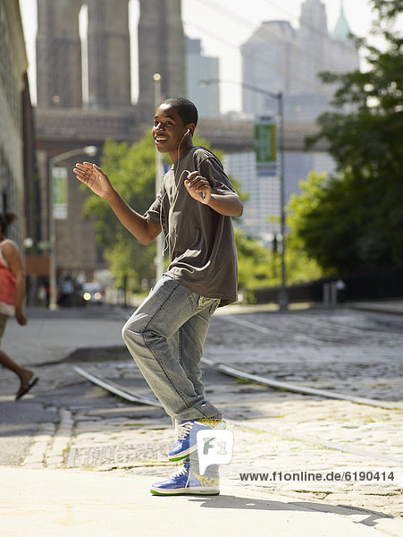 African boy dancing to music in urban setting