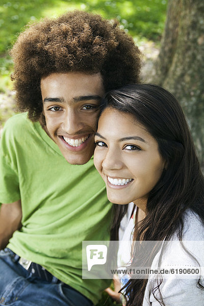 Smiling teenage couple sitting outdoors