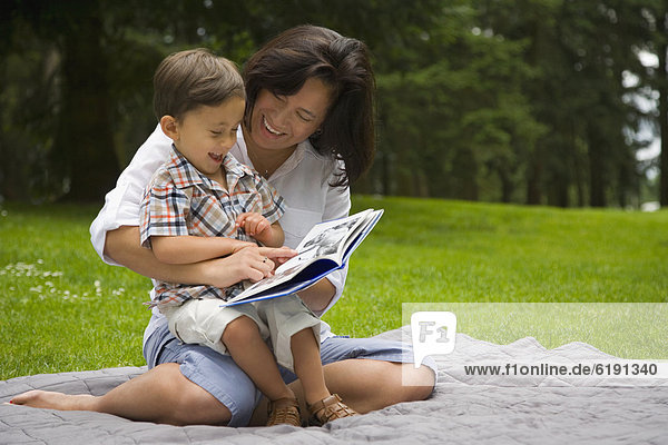 Boy reading story book in park with mother