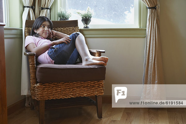 Hispanic girl sitting in armchair