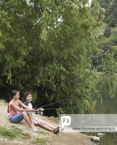 Young boy and girl fishing in lake
