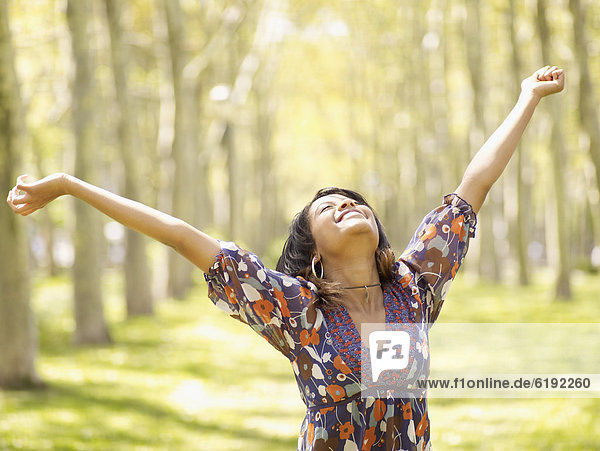 Hispanic woman with arms outstretched in park