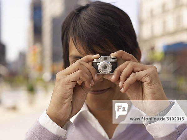 Indian man taking photograph with miniature camera