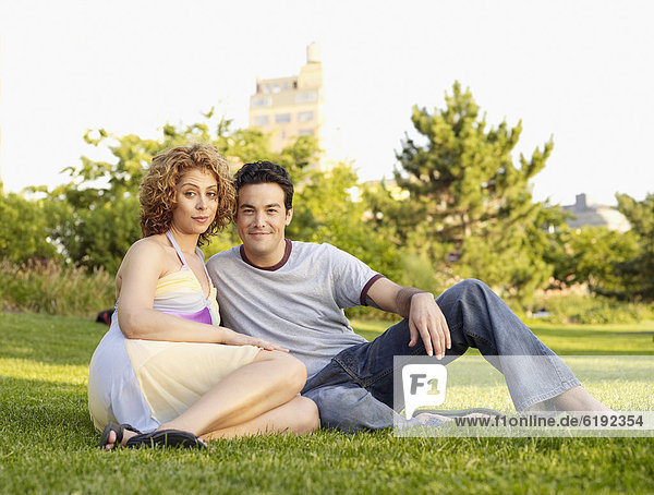 Couple sitting in grass in city park
