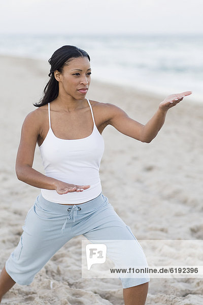 African woman practicing yoga at beach
