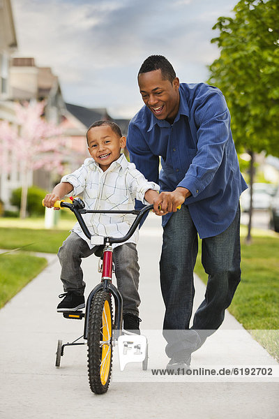Father teaching son to ride bicycle