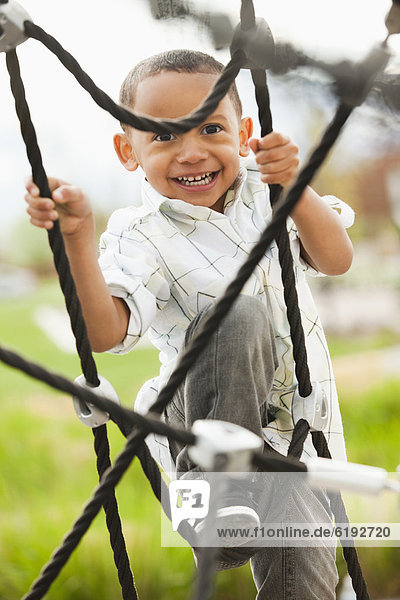 Mixed race boy climbing on structure in playground
