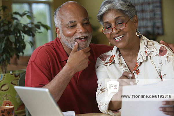 Senior African couple paying bills online