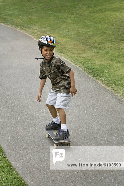 Asian boy skateboarding downhill