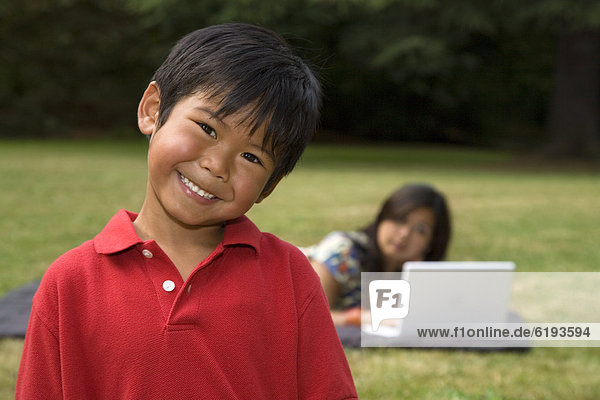 Asian boy smiling with mother in background