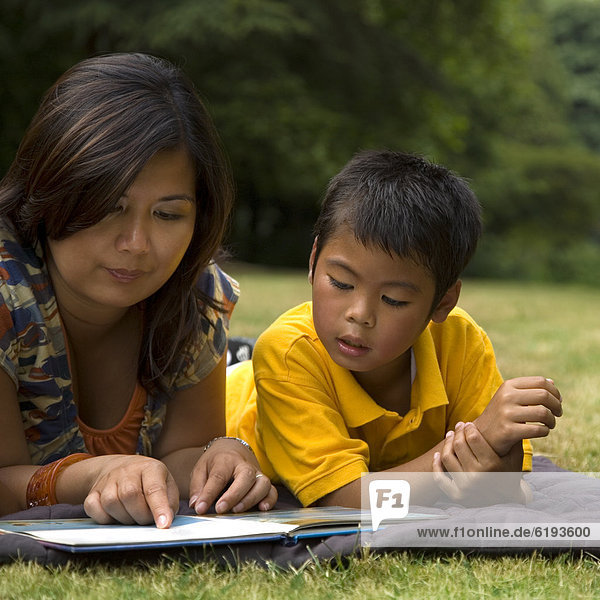 Asian mother reading book to son