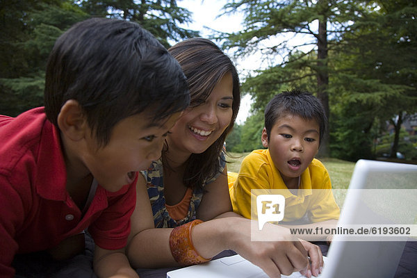 Asian mother showing sons laptop