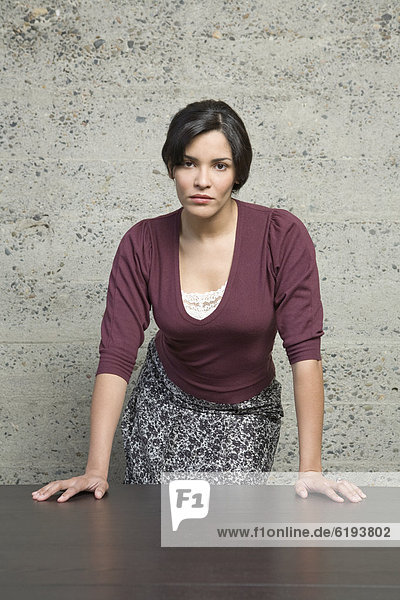 Angry Hispanic businesswoman leaning on table