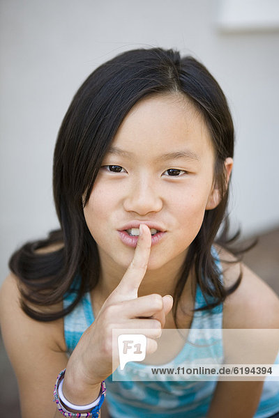 Chinese girl making shhh gesture