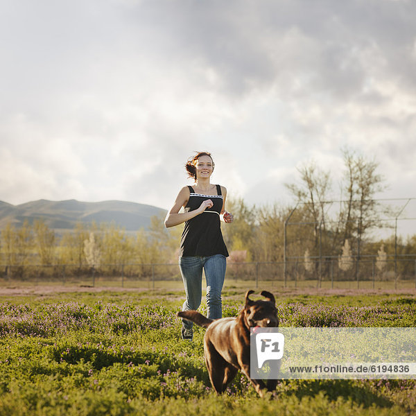 Caucasian woman running in field with dog