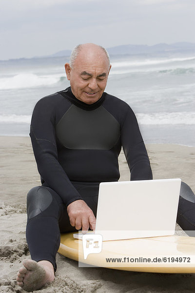 sitzend Senior Senioren benutzen Mann Notebook Hispanier Surfboard