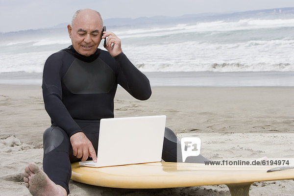 Handy sitzend Senior Senioren benutzen Mann sprechen Notebook Hispanier Surfboard