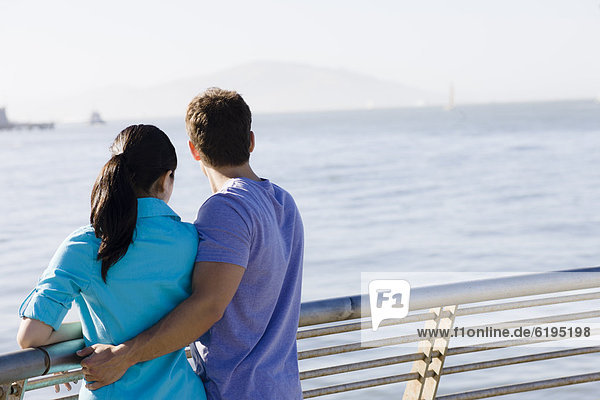 Couple leaning on railing at waterfront