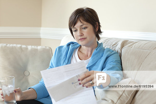 Caucasian woman on sofa reviewing bills