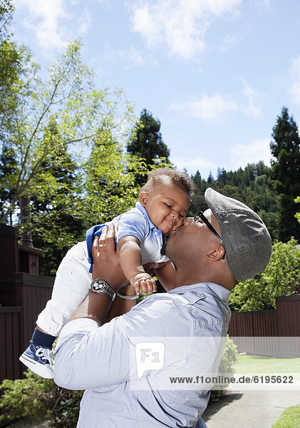 African American father lifting and kissing baby son