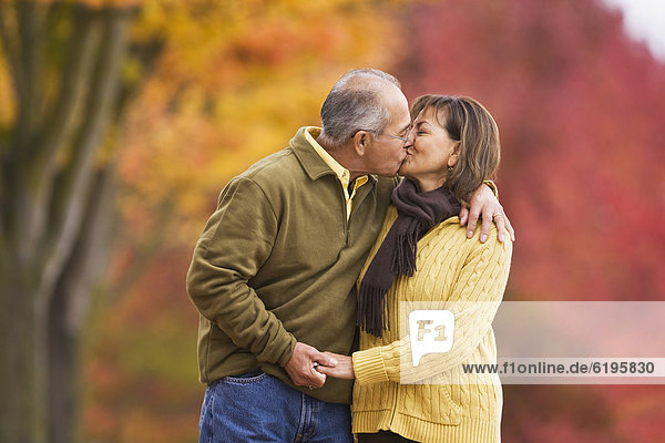 Hispanic couple kissing outdoors in autumn