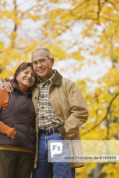 Hispanic couple hugging outdoors in autumn