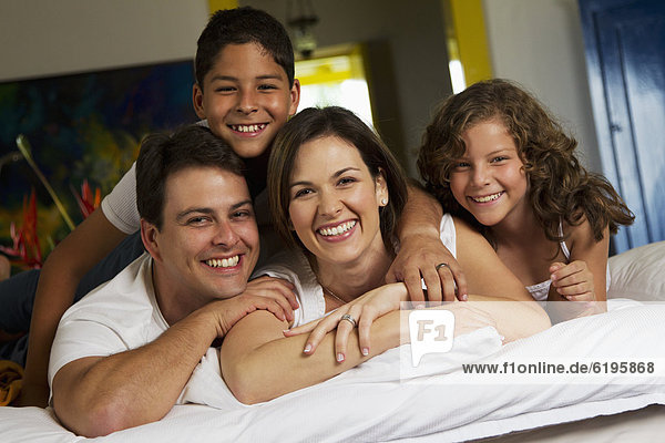 Smiling family laying on bed together