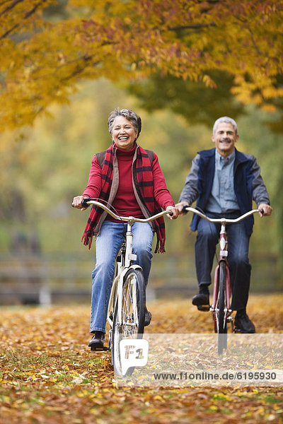 African couple riding bicycles in park in autumn