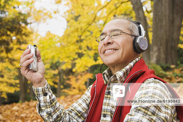 Hispanic man wearing headphones holding mp3 player
