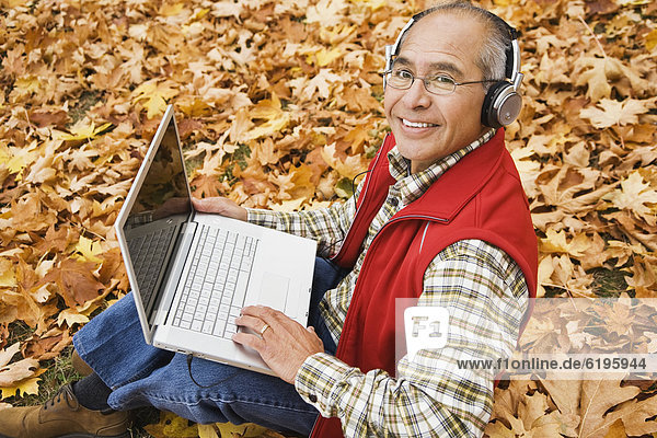 Hispanic man wearing headphones using laptop