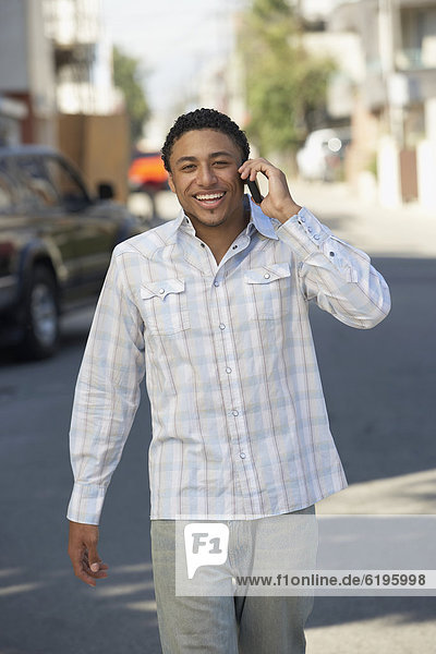 Young mixed race man in street using cell phone
