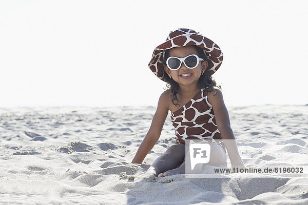 Young mixed race girl in sunglasses sitting at beach