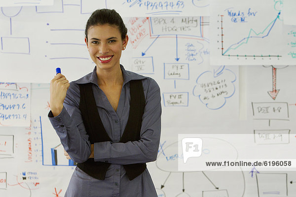 Hispanic businesswoman standing near drawings on whiteboard