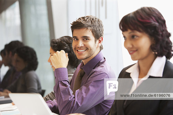 Smiling Hispanic businessman in office with co-workers