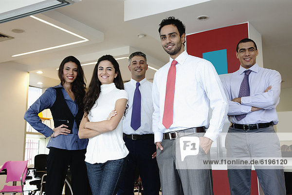 Smiling Hispanic business people standing together in office