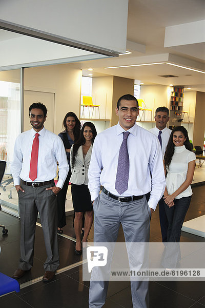 Smiling Hispanic business people standing together in office