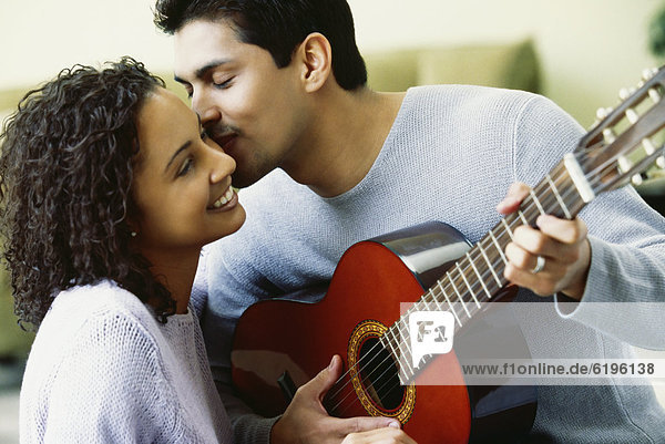 Hispanic couple with guitar kissing