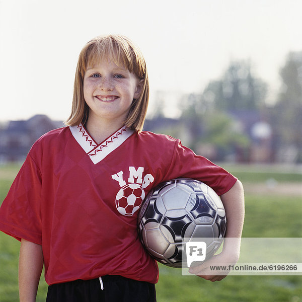 Smiling girl in uniform holding soccer ball
