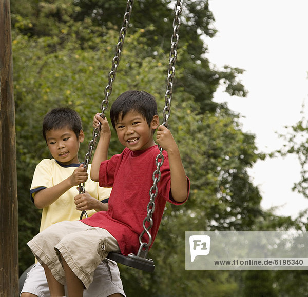 Asian boys swinging on playground