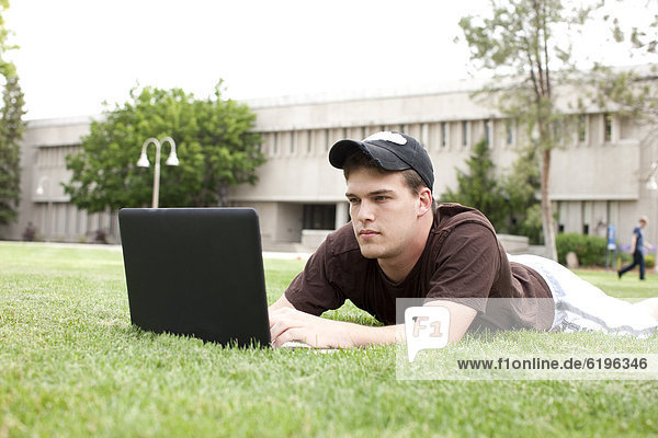 Serious Caucasian man using laptop in grass