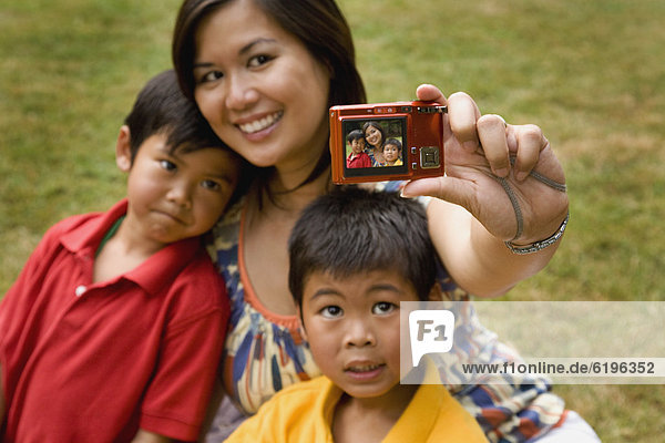 Asian mother and sons taking self-portrait